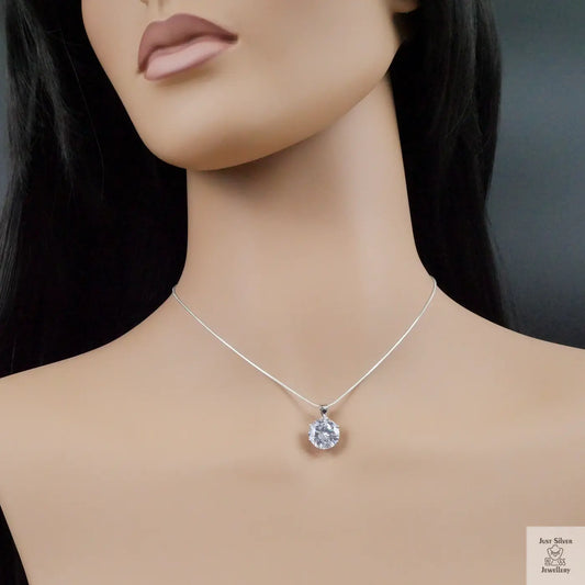 Mannequin wearing a silver necklace with a round pendant on a dark background