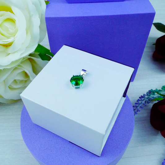 Green gemstone pendant in a white box with purple and floral background
