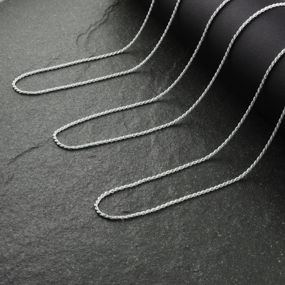 Silver chain on a dark textured surface