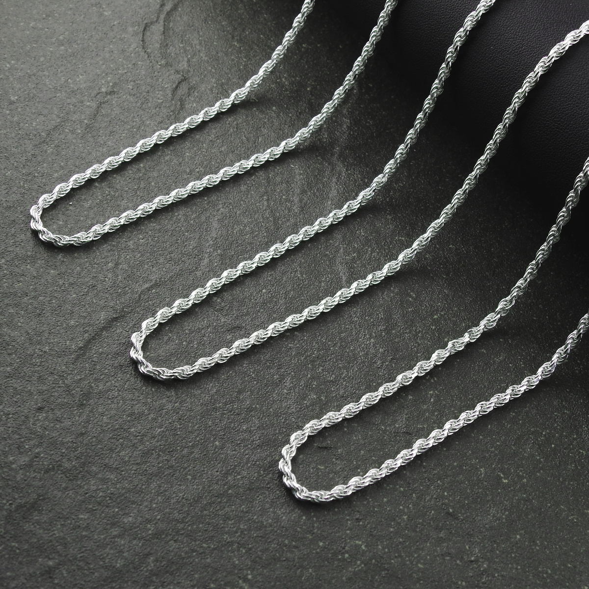 Silver rope chain on a dark textured surface