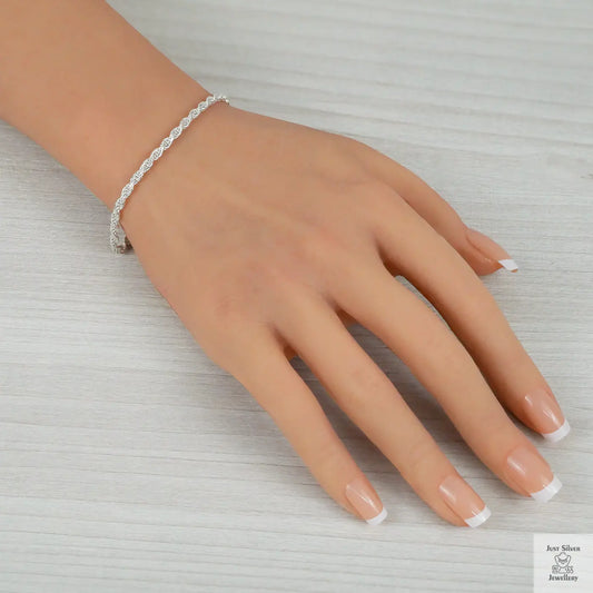 Hand wearing a silver bracelet on a light gray background