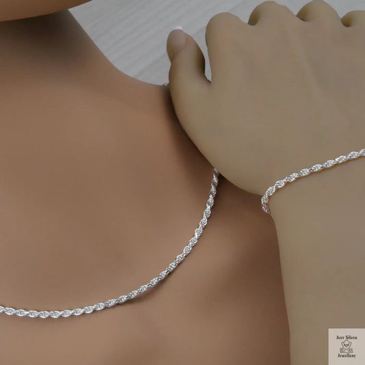Silver rope necklace and bracelet on a person's neck and wrist against a neutral background