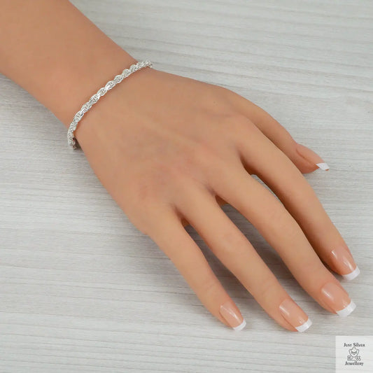 Silver bracelet on a hand with a neutral background