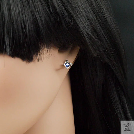 Earring worn by a person with dark hair on a neutral background