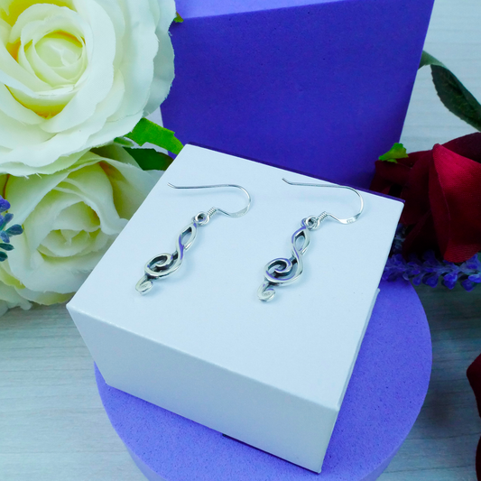 Silver earrings on a white box with flowers in the background