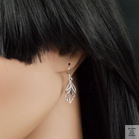 Silver leaf-shaped earring worn by a person with dark hair.