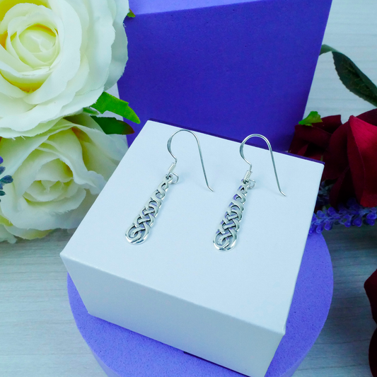 Silver earrings on a white box with flowers in the background