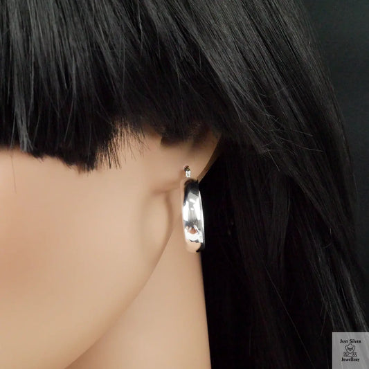 Silver hoop earring worn by a mannequin with black hair.