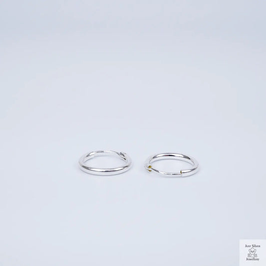 Two silver hoop earrings on a light grey background