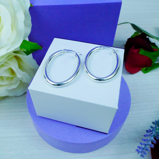Silver hoop earrings on a white box with flowers in the background