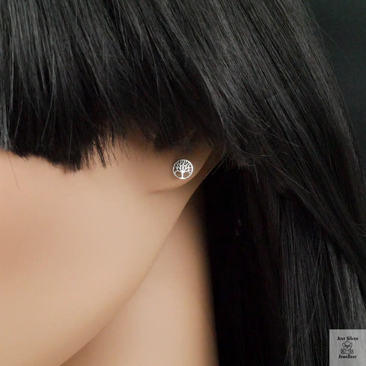 Silver tree-of-life earring on a mannequin ear against a dark background