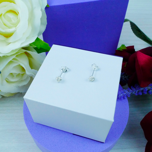 Silver earrings in a white box with flowers in the background
