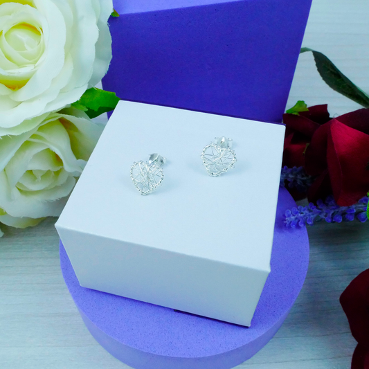 Silver earrings in a white box with flowers in the background