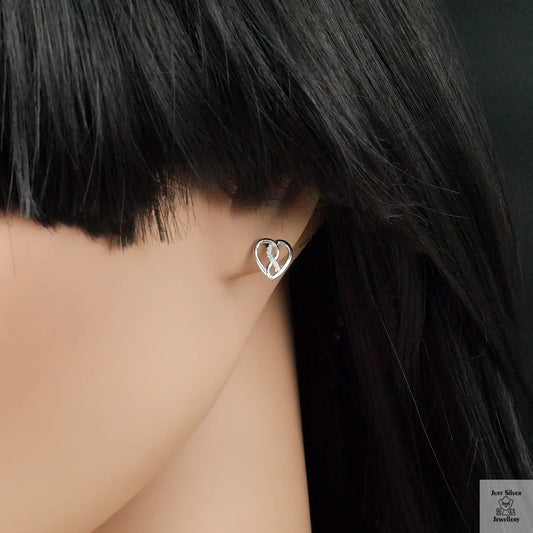 Heart-shaped earring worn by a person with dark hair