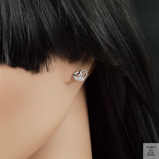Silver heart-shaped earring worn by a person with black hair.