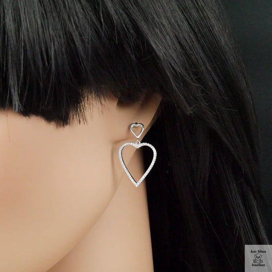 Heart-shaped earrings worn by a person with black hair.