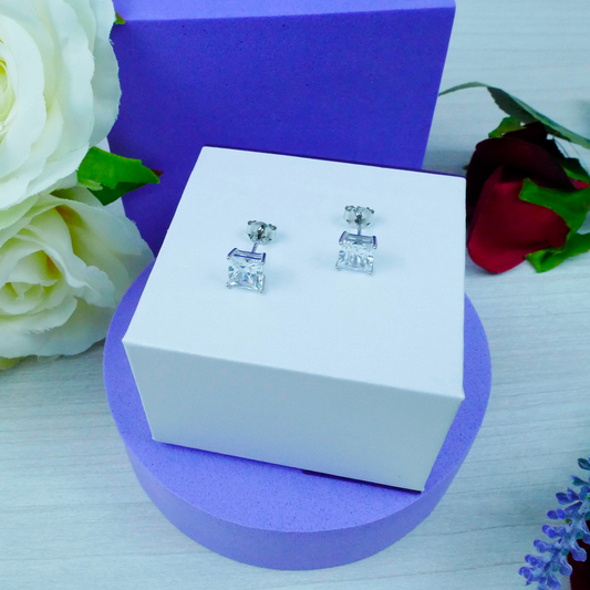 Silver earrings on a white box with purple base and floral decorations