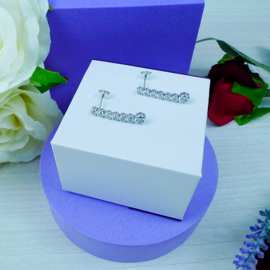 Silver earrings on a white box with purple base and floral decorations