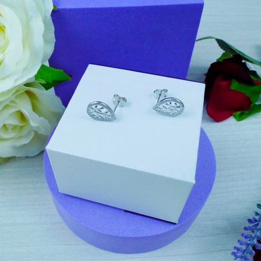 Silver earrings on a white box with flowers in the background