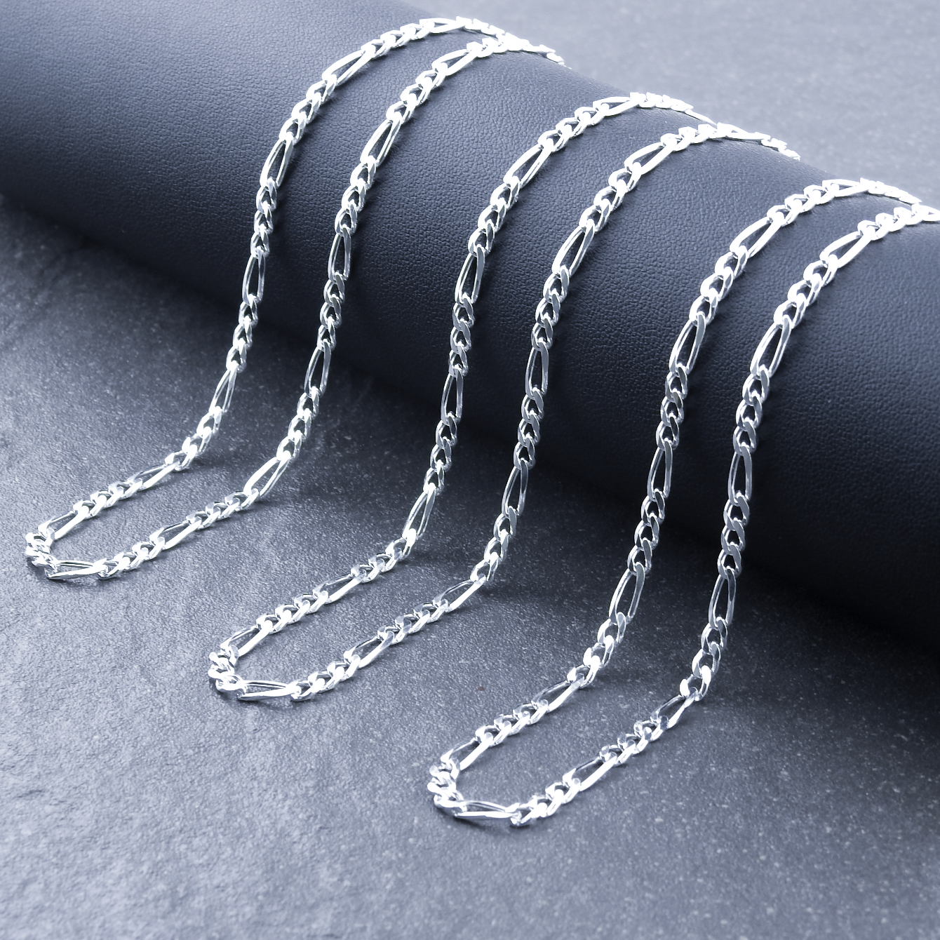 Silver chain necklace on a dark gray surface