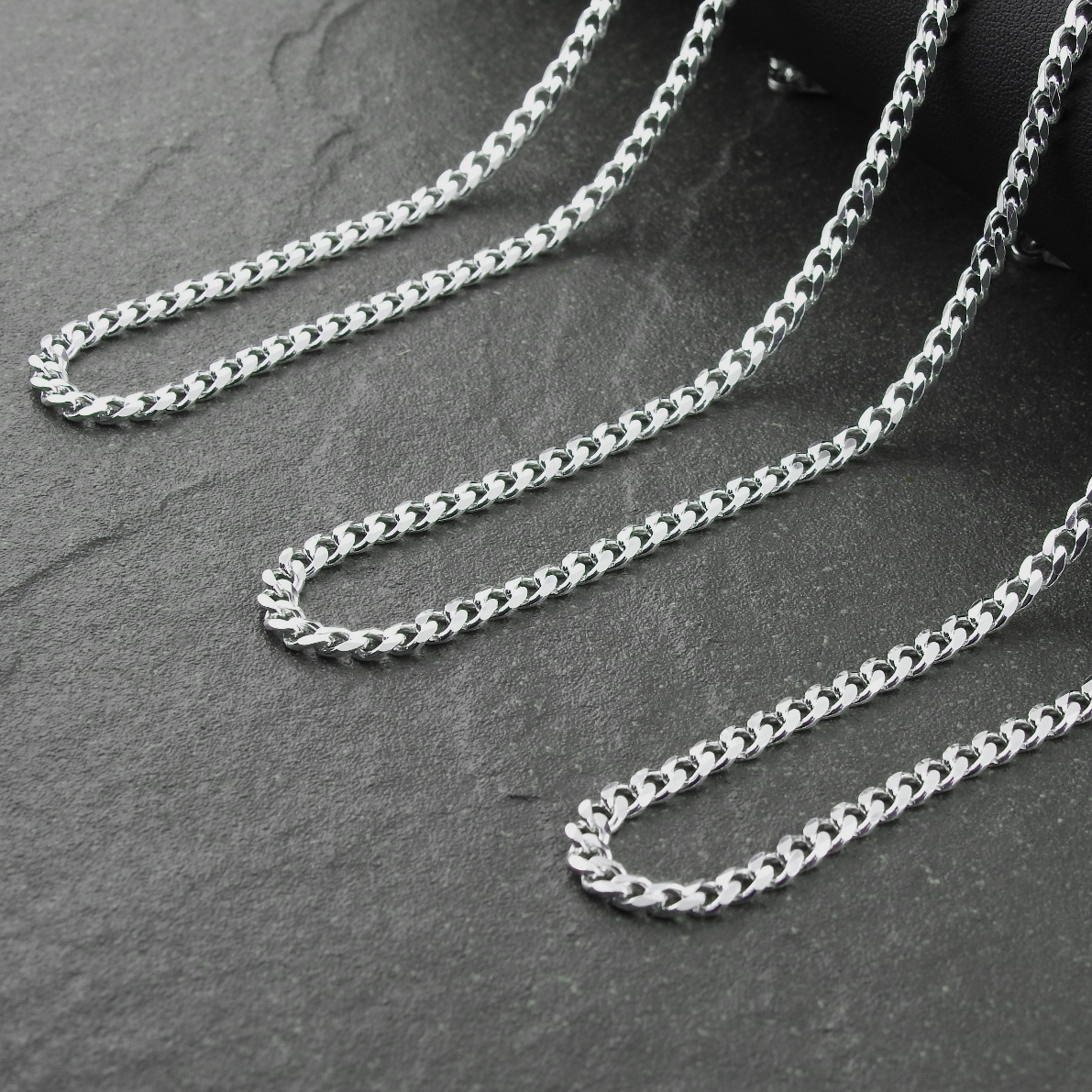 Silver chain necklace on a dark stone surface