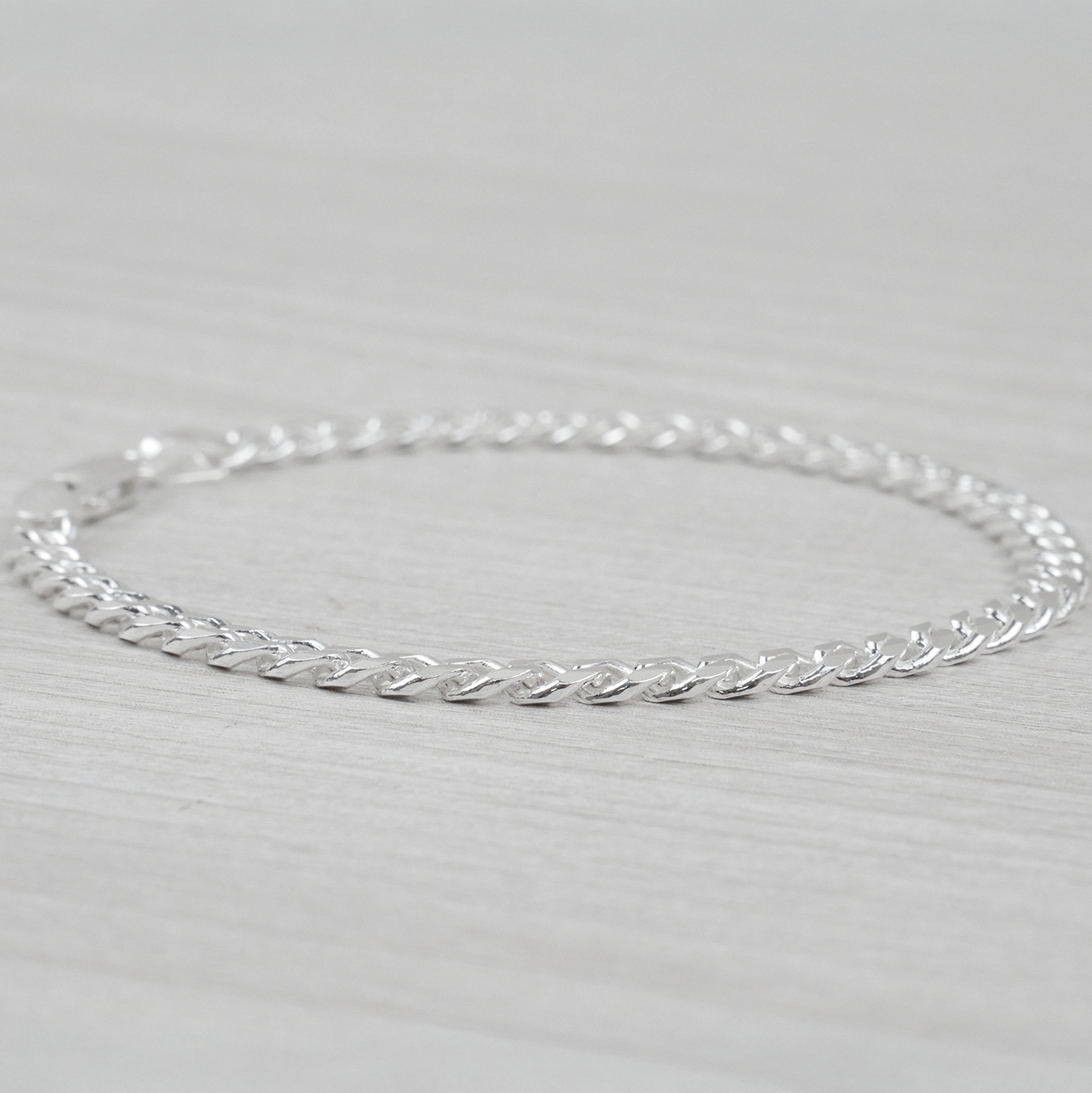 Silver curb bracelet on a light gray background