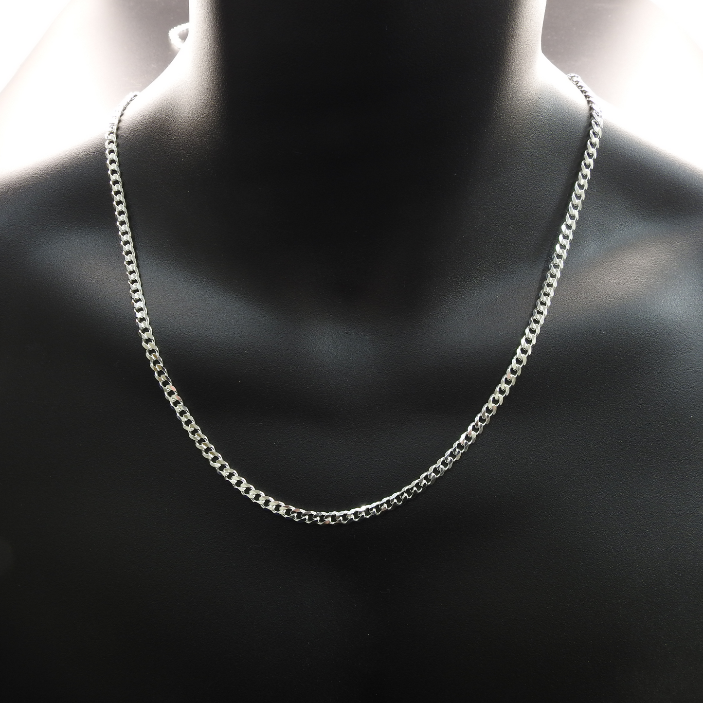 Silver chain necklace on a mannequin neck against a dark background