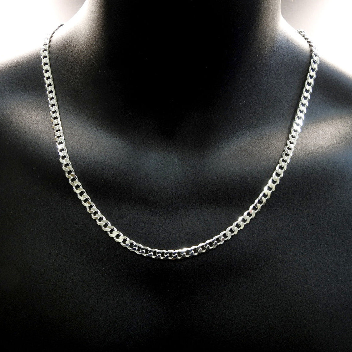 Silver chain necklace on a black mannequin bust.