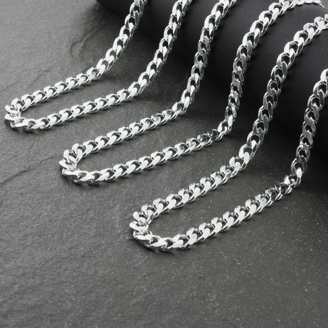 Silver chain necklace on a dark stone surface
