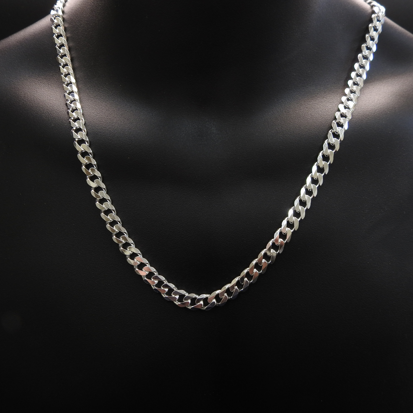 Silver chain necklace on a black mannequin bust.
