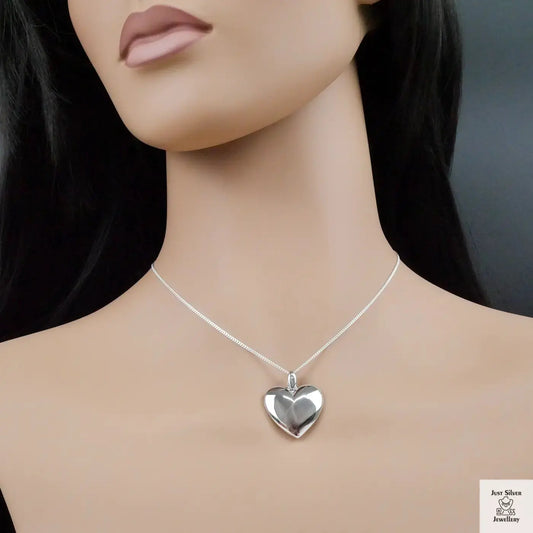 Mannequin wearing a silver heart-shaped necklace on a plain background