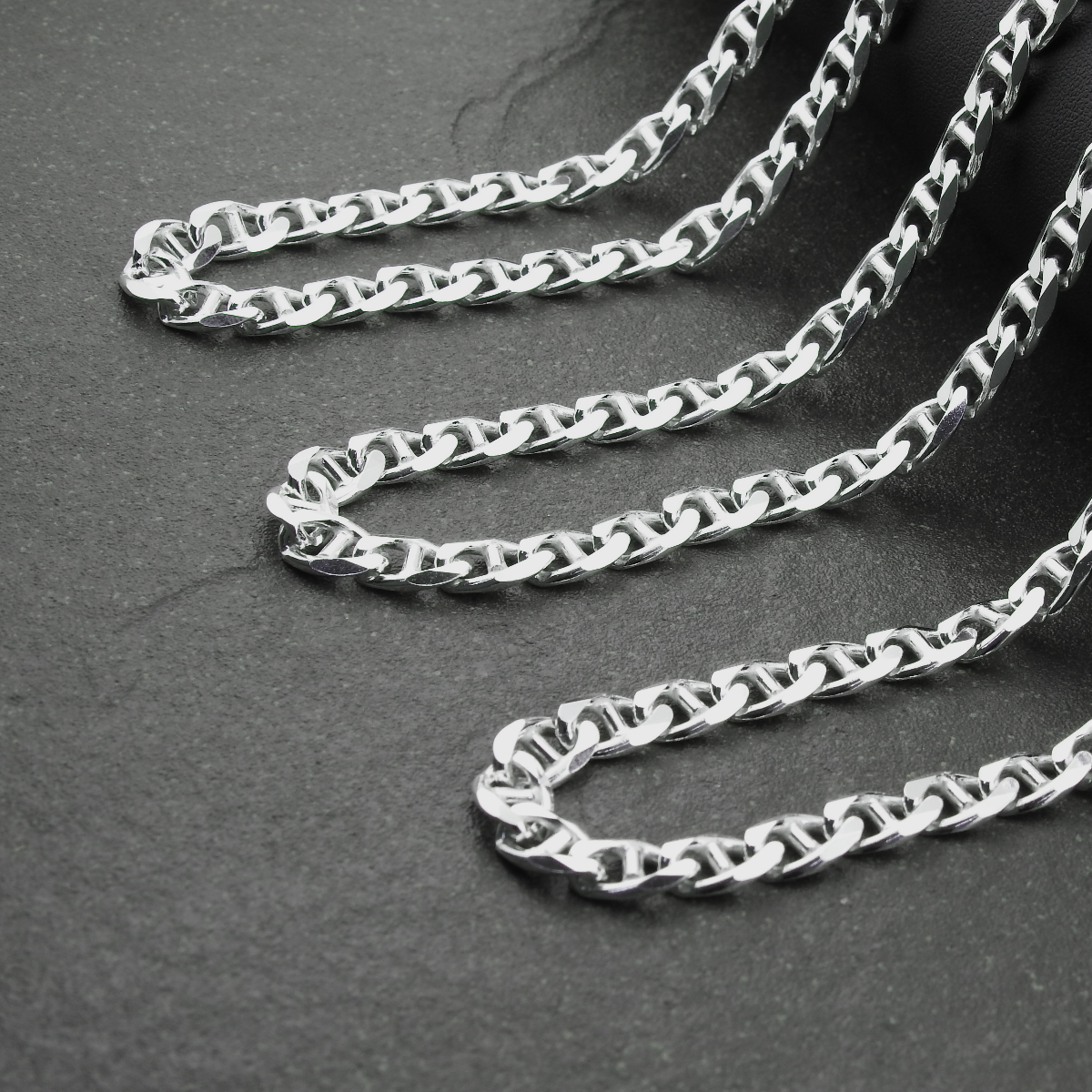 Silver chain necklace on a dark gray surface