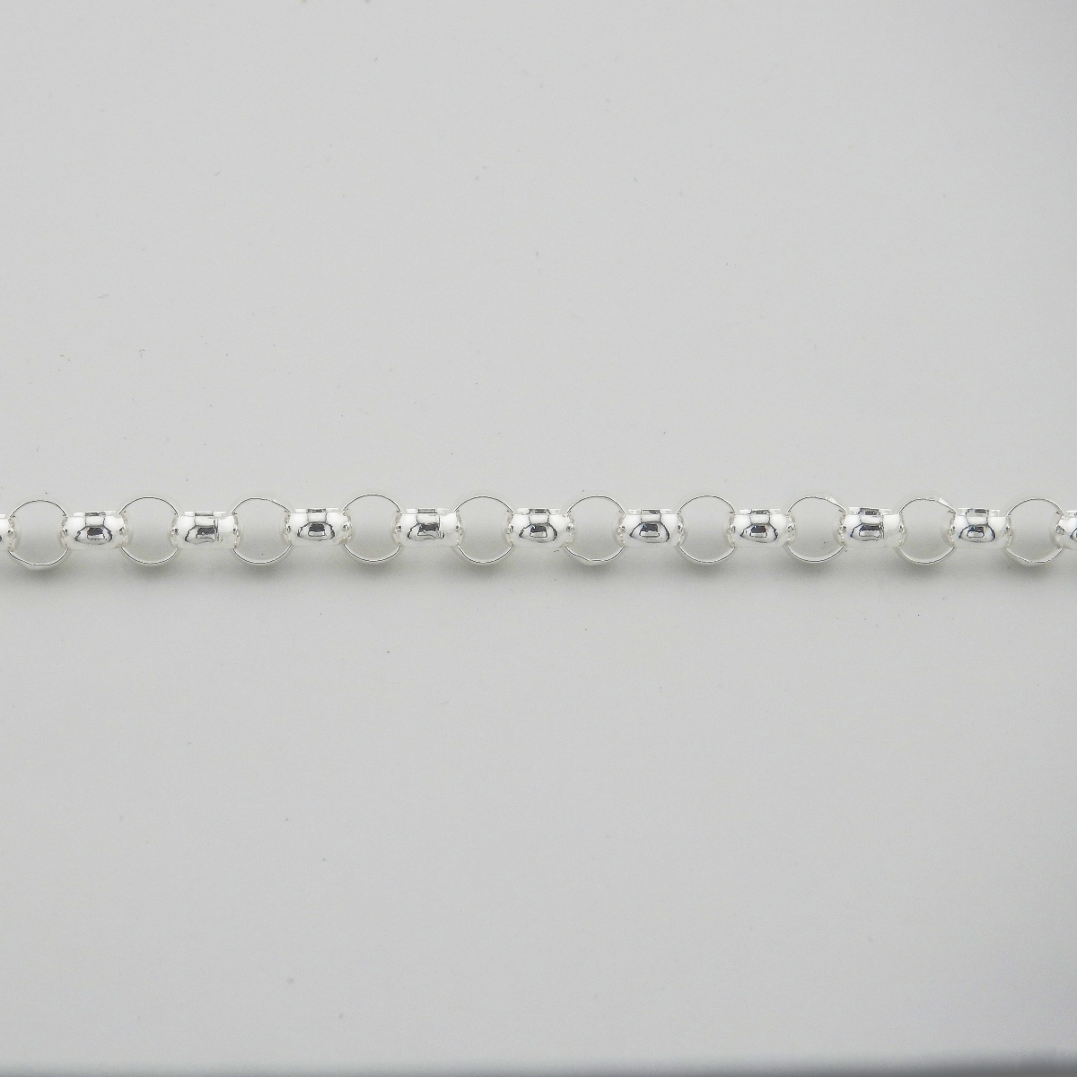 Close-up of a silver beaded necklace on a light gray background