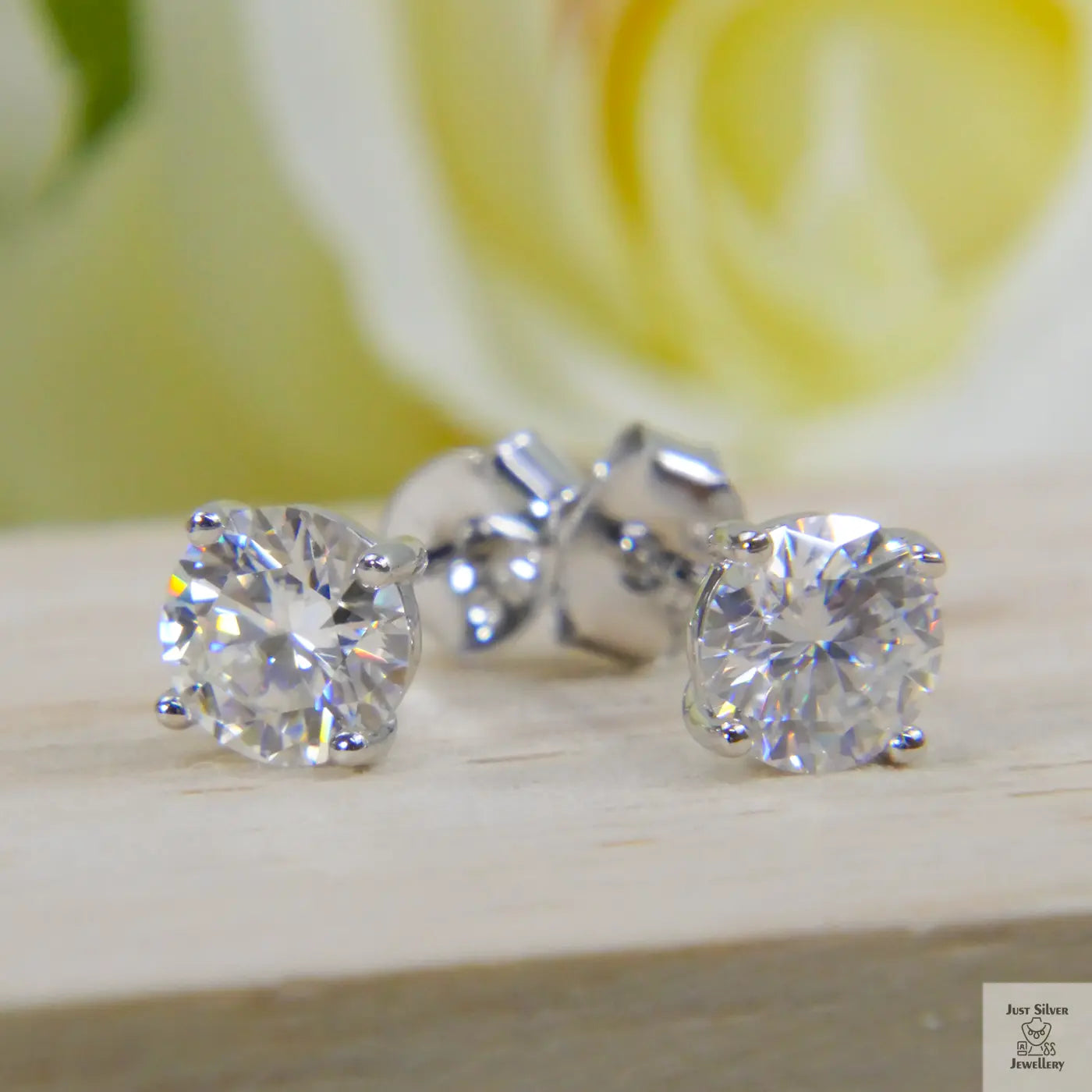 Natural Zircon stud earrings on a wooden surface with a blurred yellow flower in the background