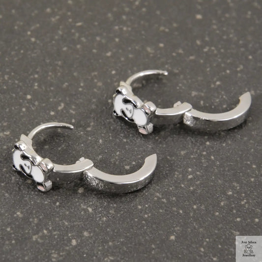 Pair of silver claw-shaped earrings on a gray surface