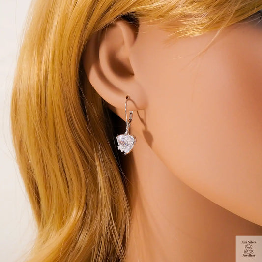 Close-up of a person wearing a heart-shaped earring with blonde hair.