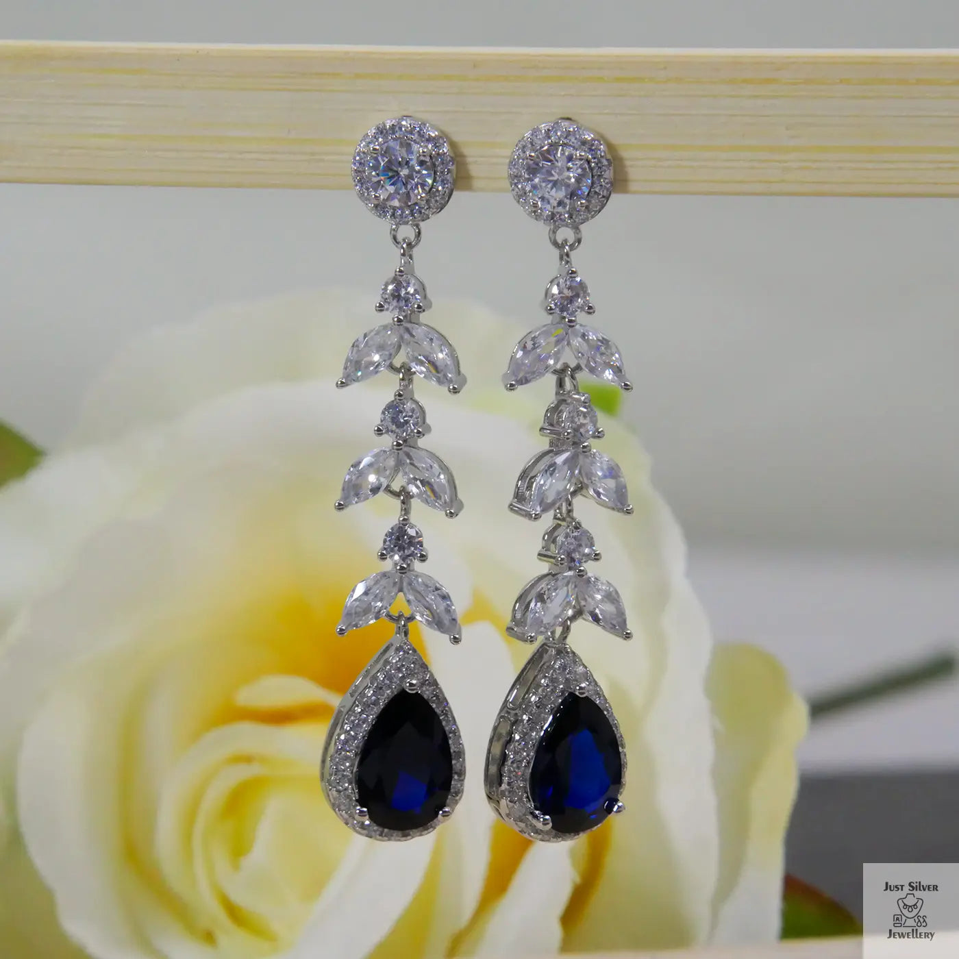 Silver earrings with blue natural zircon gemstones on a rose background