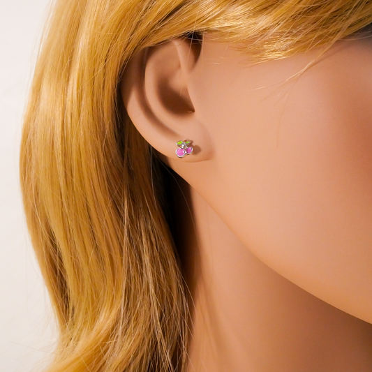 Close-up of an ear wearing colorful stud earrings with blonde hair.