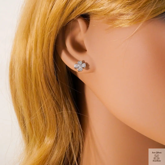 Close-up of a person wearing a silver flower-shaped earring with blonde hair.