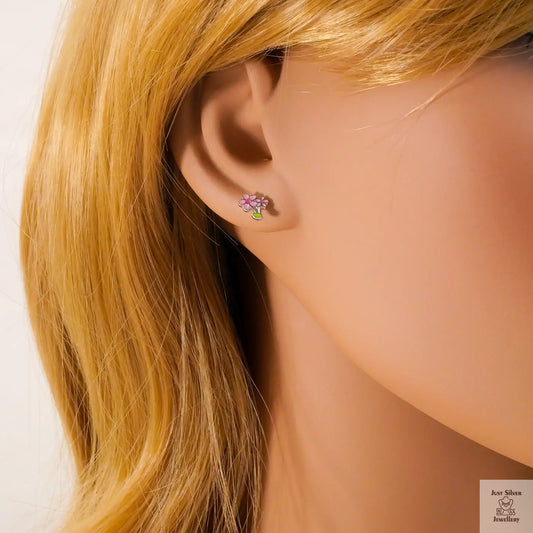 Close-up of a woman wearing a floral stud earring with blonde hair.
