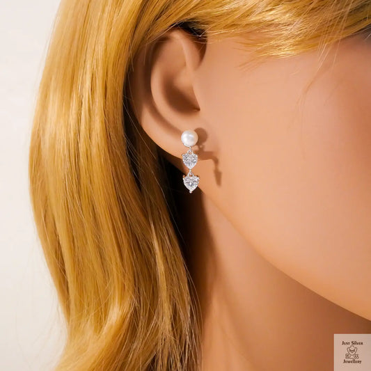 Pearl and heart-shaped Natural Zircon gemstone earrings on a mannequin with blonde hair.