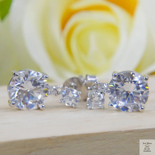Set of Natural Zircon stud earrings on a wooden surface with a blurred rose background