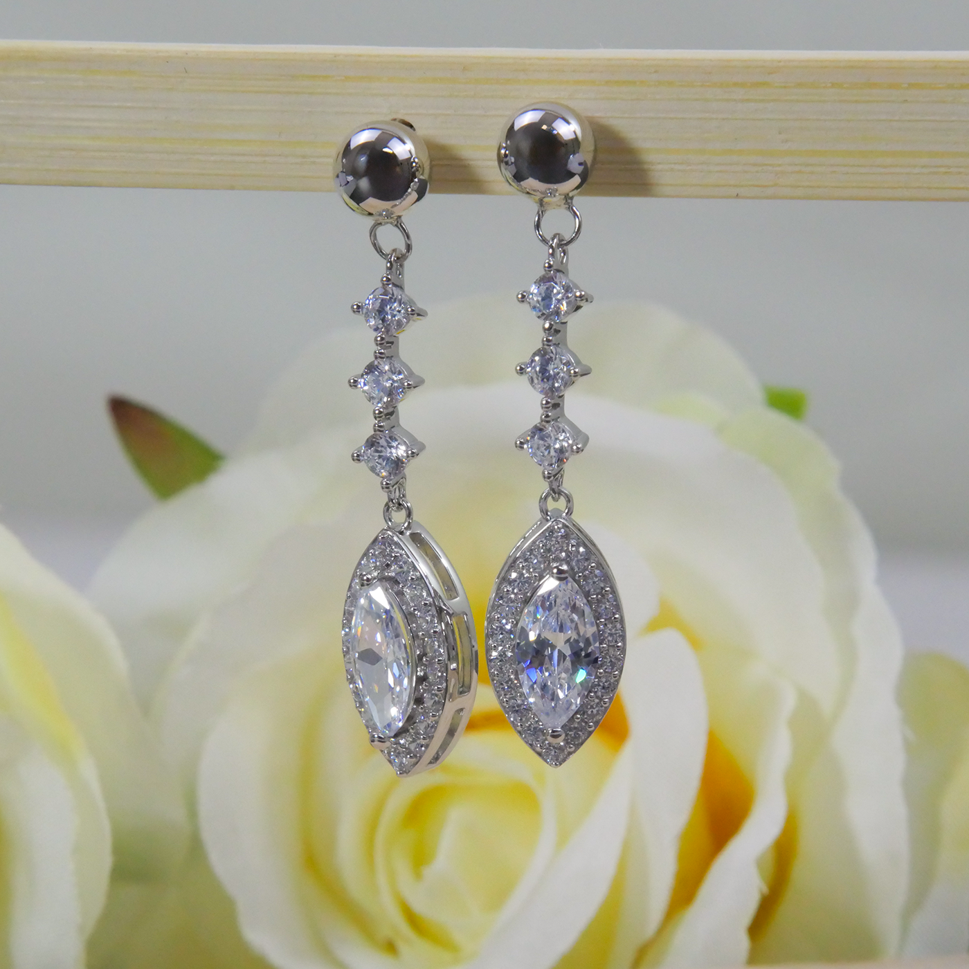 Silver earrings with natural zircon clear stones on a rose in the background