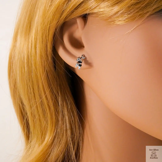 Close-up of an ear wearing a small earring with blonde hair.