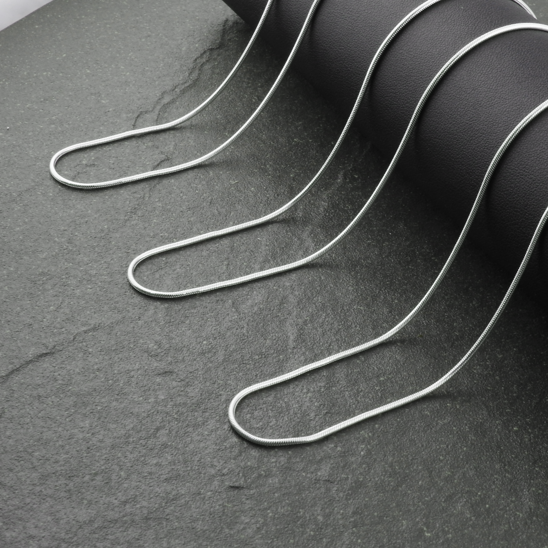 Silver necklace on a dark stone surface