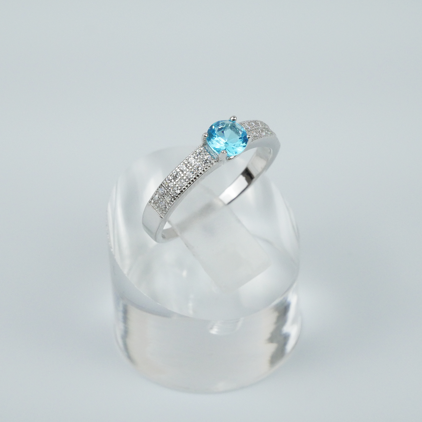 Silver ring with a blue gemstone on a light gray background