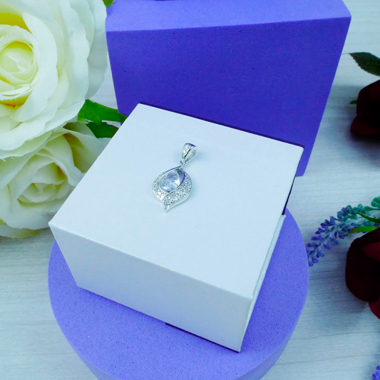 Jewelry pendant in a white box with purple base and white roses in the background