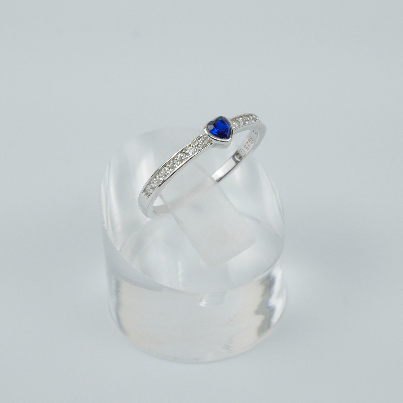 Silver ring with a blue gemstone on a light gray background