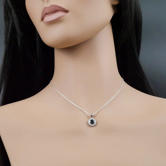 Mannequin wearing a silver necklace with a black pendant on a dark background
