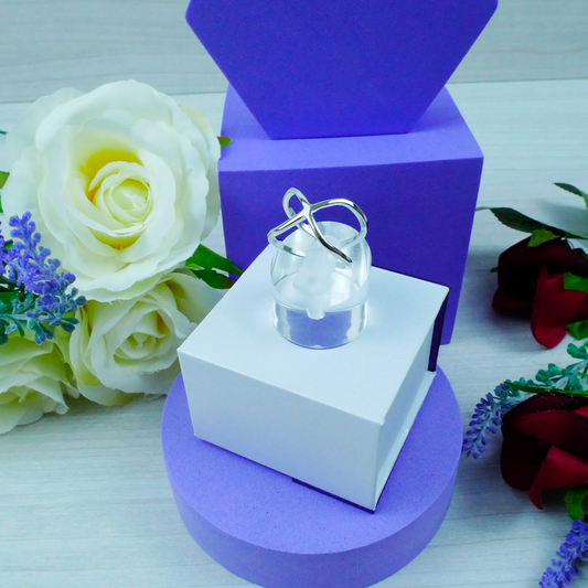 Clear glass ring on a white box with purple base, surrounded by flowers
